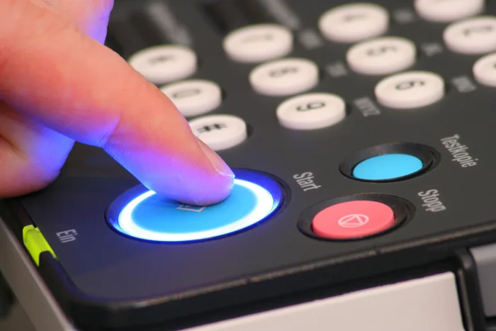 Finger pressing the illuminated start button on a leased copier's control panel